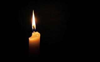 Burning white candle on black background. Close-up photo. With copy space. Image for memory of events and people photo