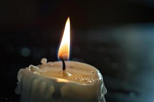Burning white candle on black background. Close-up photo. With copy space. Image for memory of events and people photo