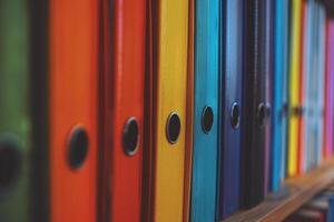 un grande número de de colores aglutinantes para documentos en pie en fila en estante foto