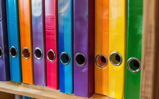 A large number of colored binders for documents standing in row on shelf photo