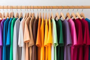 rack of T-shirts of different colors hanging on hangers. Fashionable and varied clothing concept photo