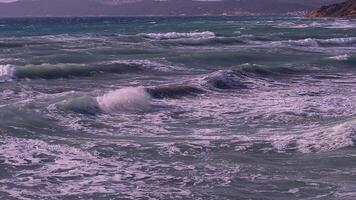 fuerte olas y salpicaduras estrellarse y salpicaduras en el rocas en un soleado día y áspero mar. profundo azul color. poderoso mar olas rotura terminado rocas en playa megas limnionas, Quíos, Grecia video