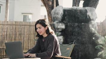 Young Asian woman typing on laptop computer at cafe. work from anywhere concept video