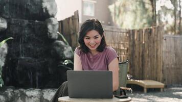 online Treffen über Internet. freundlich asiatisch Frau Gruß Herstellung Anruf mit Laptop im Cafe, winken Hand beim Kamera. Arbeit von irgendwo Konzept video