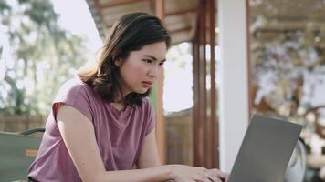 eccitato giovane donna vincitore sembra a il computer portatile celebrare in linea successo si siede a bar. asiatico signora ottenere nuovo distanza lavoro opportunità, leggere bene notizia nel e-mail, gioisce vittoria, sentire motivata video