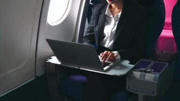 bem sucedido ásia o negócio mulher, o negócio mulher trabalhando dentro avião cabine durante voar em computador portátil computador video