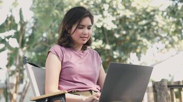 Young Asian woman typing on laptop computer at cafe. work from anywhere concept video