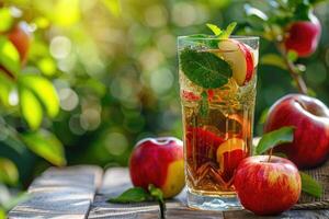 A glass of apple juice surrounded by green and red apples, some whole and some sliced. photo