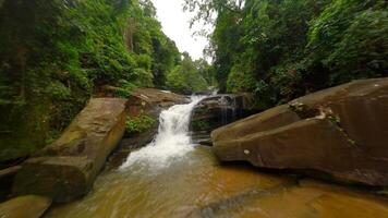 glad fpv vlucht over- trapsgewijs rivier- en waterval in regenwoud, Thailand video