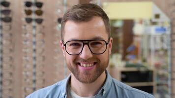 Portrait of a young man in new glasses in optics shop video