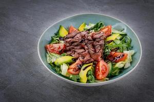 Tasty salad - roasted veal loin, avocado, boiled eggs and fresh vegetables on stone table 1 photo