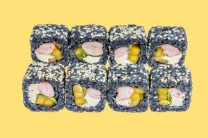 rolls with black rice, shrimp and avocado on a yellow background photo