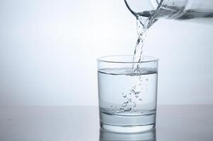 Drinking water is poured into a glass from a jug photo