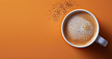 Top View of a Cup of Coffee With Cinnamon Sprinkles on an Orange Background photo