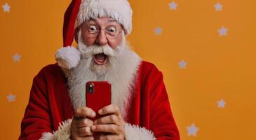 sorprendido Papa Noel claus utilizando teléfono inteligente en contra naranja antecedentes con oro estrellas foto