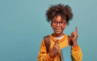 Happy Young Girl With Backpack Pointing Up Against A Blue Background photo