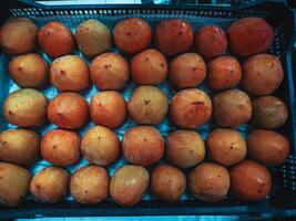 Box with thirty five fresh persimmons in supermarket on the shelf, fruit store, close up. photo