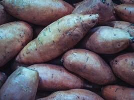 Pile of sweet batata, potato in supermarket on the shelf. Food background photo