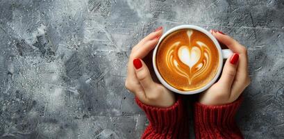 Womans Hands Holding a Cup of Latte Art on a Blue Background photo