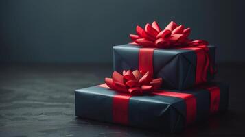 Two Navy Blue Gift Boxes With Red Ribbons On A Dark Surface photo