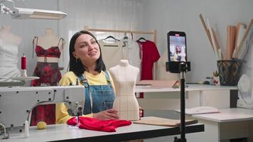 Girl runs a design blog about tailor-making. She films herself on her phone, against the background of her atelier. Medium shot. Slow motion. video