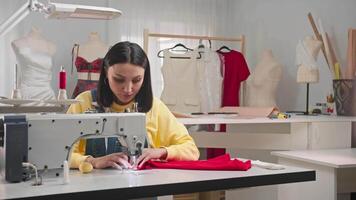 Seamstress is embroidering on a sewing machine in her small but beautiful studio. She has started her own small business. Medium shot. Slow motion. video