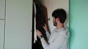 Jeune homme regards pour vêtements à l'intérieur une placard video