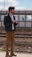 jung Mann Verwendet das Telefon während warten zum das Zug beim das Bahnhof video