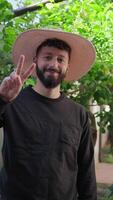 gelukkig Mens met ronde hoed maakt zege teken met zijn hand- video