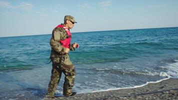 Military man in camouflage runs along the beach video