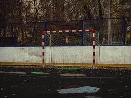 empty red white football goal on field in the city with trees on a background photo