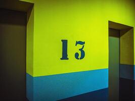 thirteen floor with number on yellow wall near lift, elevator photo