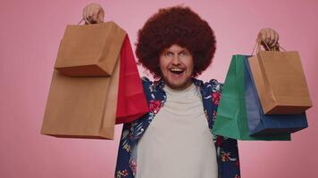 Happy tourist man showing shopping bags, advertising holidays discounts, amazed with low prices video