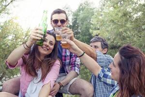 contento grupo de joven amigos tostado con cerveza foto