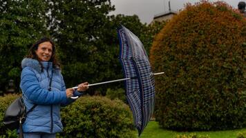 beautiful middle aged woman opening umbrella outdoors in the rain splashing water drops photo