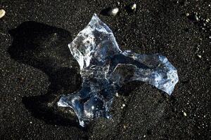 piece of ice on a black volcanic beach in iceland photo