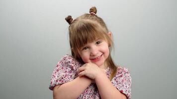 Contexte de enfants émotions, une portrait de une mignonne fille étreindre se. le sourire et bonheur de enfance. haute qualité 4k métrage video