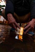 man in blue sneakers bending over a puddle showing the victory sign with his hands on a city street photo