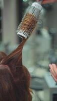 une professionnel coiffeur fait du une femme coiffant avec une brosse. mode de vie beauté procédures et les filles coiffure. haute qualité 4k métrage video