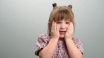 Background of children's emotions, a portrait of a girl covering her face and smiling. The child is playing hide and seek, a happy childhood. High quality 4k footage video