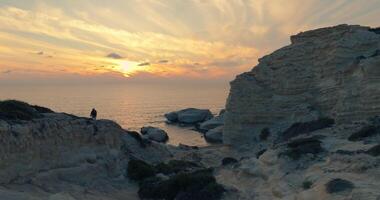 Aerial view of white cliffs at sunset on the island of Cyprus. The sun's rays create a line in the sea in a nature landscape with rocks and cliffs. High quality 4k footage video
