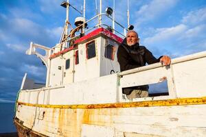 Middle-aged man playing captain on a boat stranded on an Icelandic beach photo