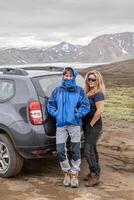 two middle aged female travelers posing near a car in a wilderness area of Iceland photo