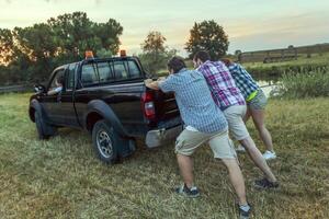 group of friends pushing the broken car photo