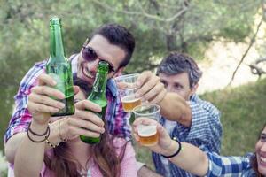 contento grupo de joven amigos tostado con cerveza foto