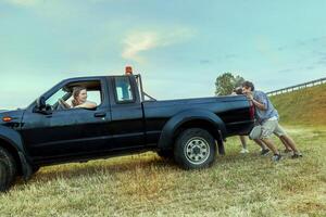 group of friends pushing the broken car photo