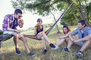 grupo de joven adultos tener divertido y comiendo foto