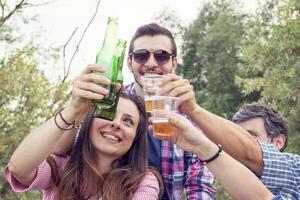 contento grupo de joven amigos tostado con cerveza foto