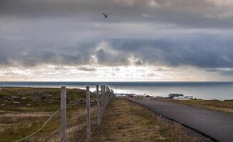 cloudy landscape of a paved road in the middle of nature towards a small village photo