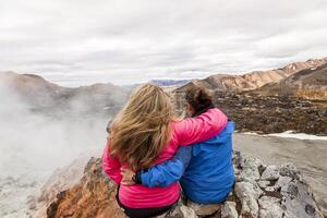 two female traveling friends hugging each other watching the landscape photo